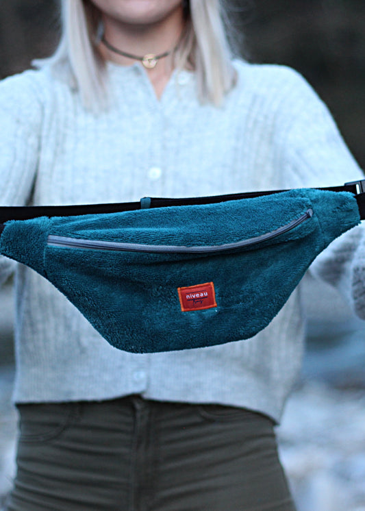 Banane en éponge bleu pétrole, zip gris, sangle noire, logo devant.