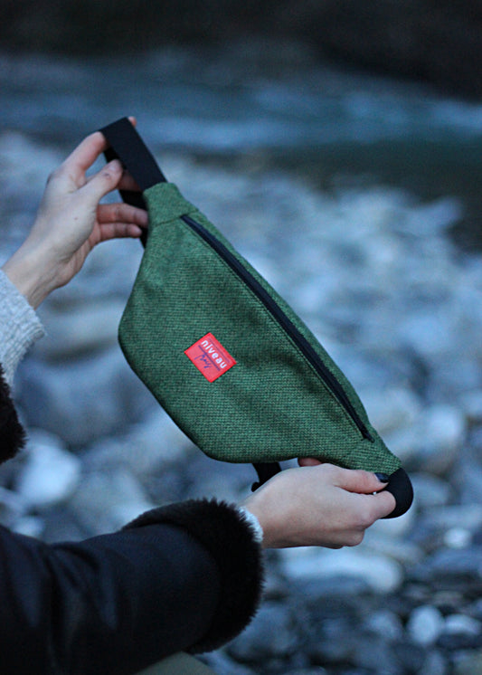 Banane Tchikita en lainage vert, sangle noire, zip noir, logo sur le devant.