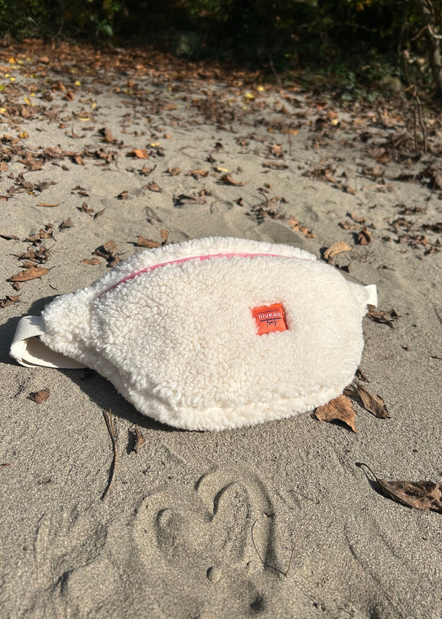 Banane en tissu sherpa beige, vue d'ensemble dans le sable