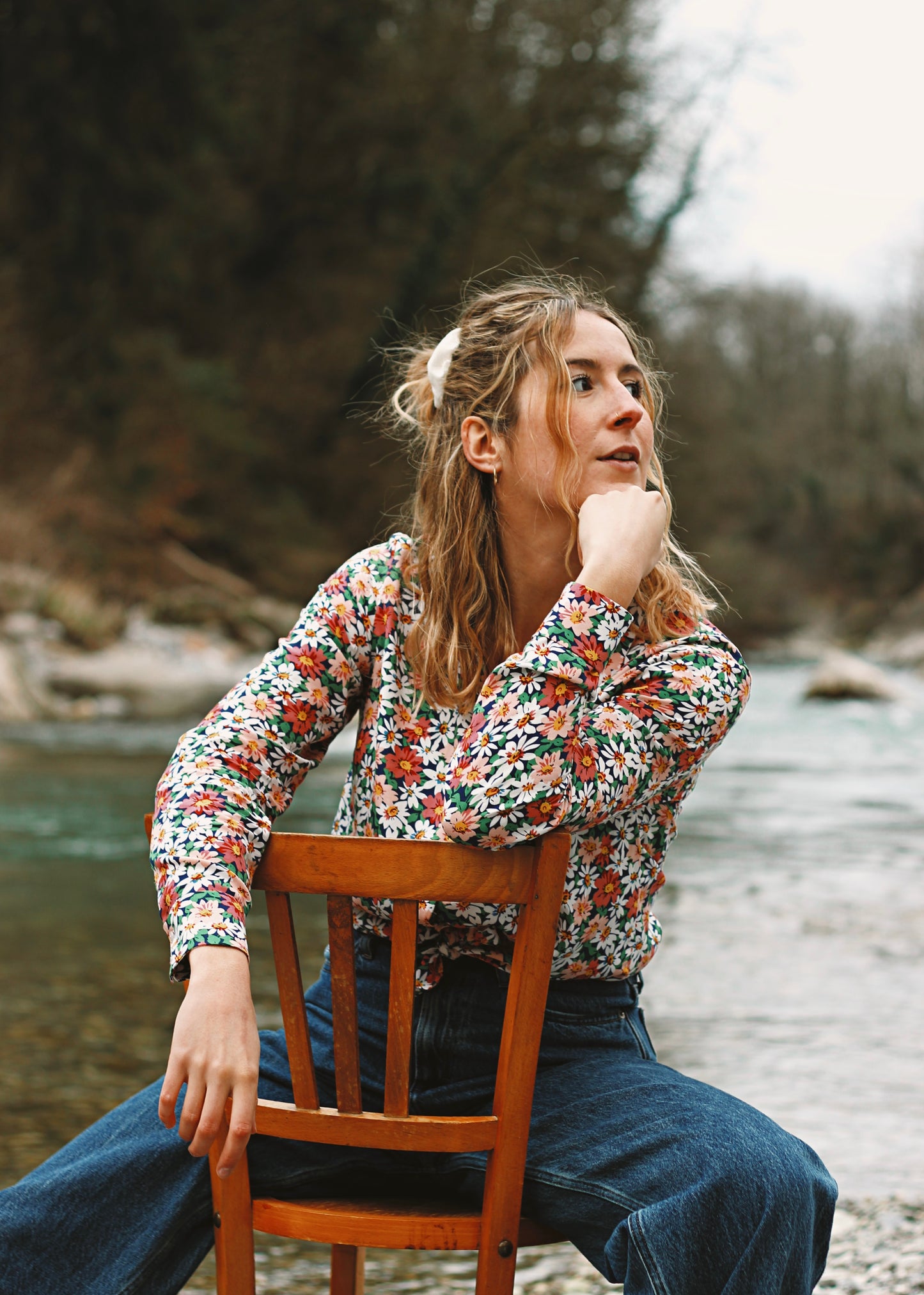 Femme portant le chemisier Iris, assise sur une chaise au bord de l'eau