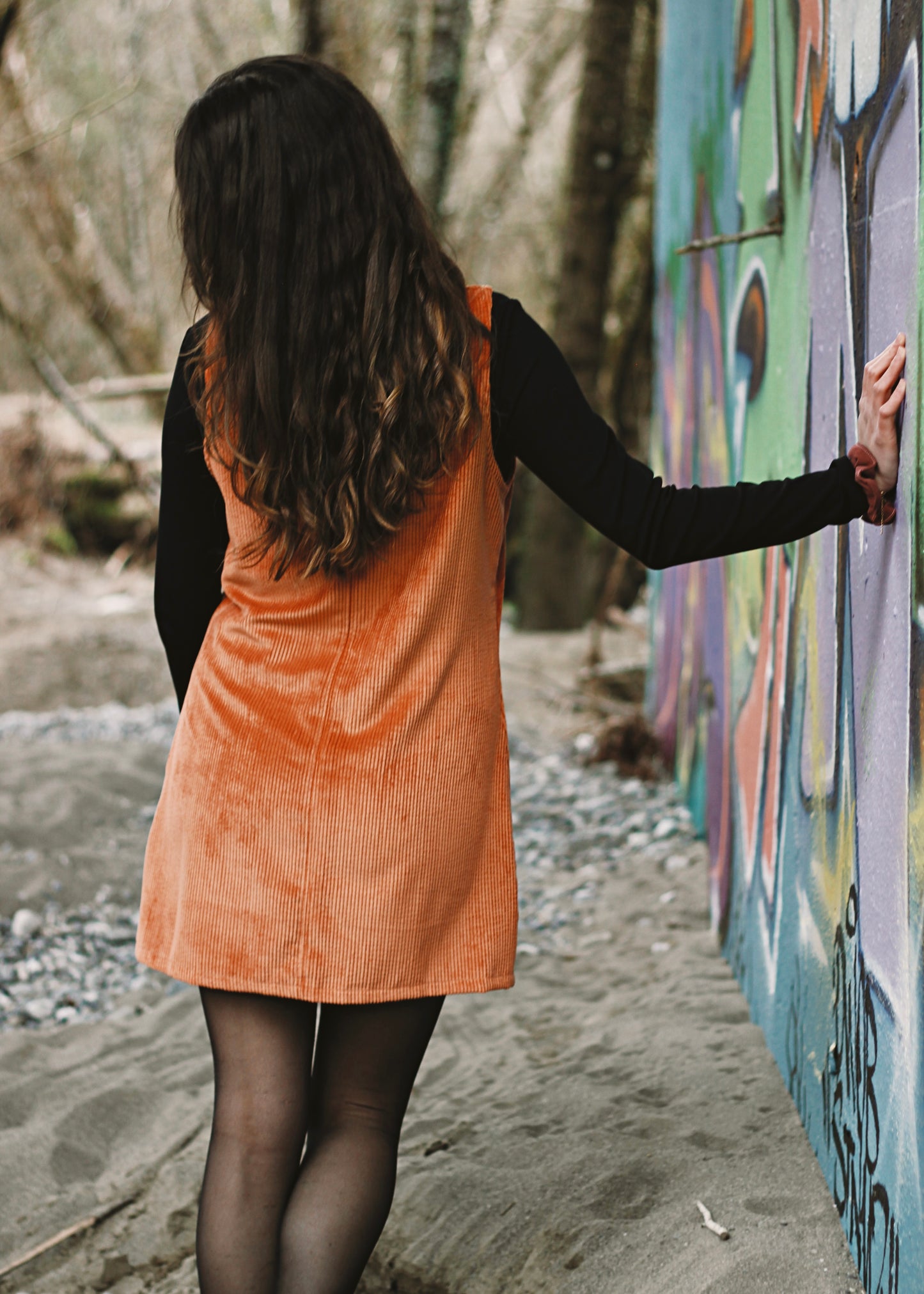 Femme portant la robe Nyssa brique, le long d'un mur.