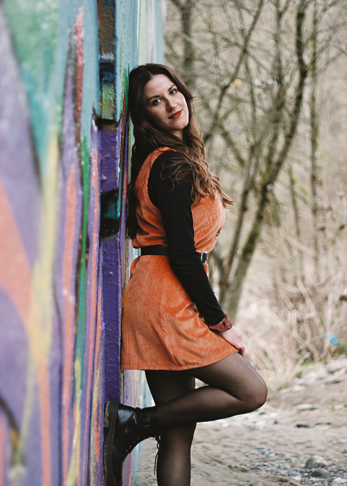 Femme portant la robe Nyssa brique ceinturée, adossée à un mur.