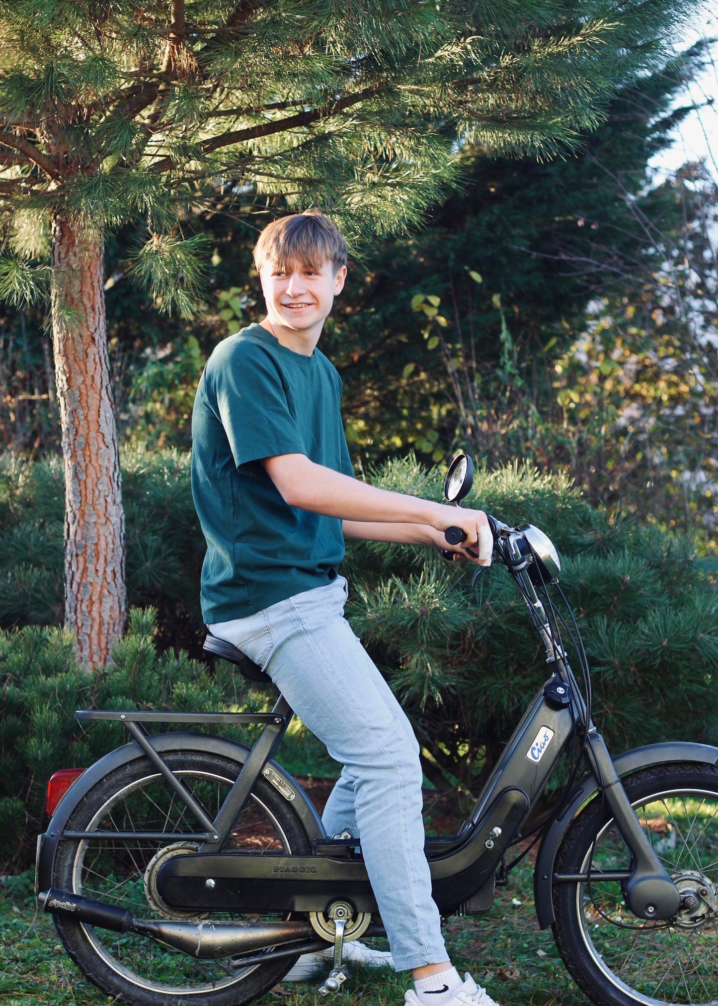 Jeune homme sur une mobylette, portant le t shirt Dama vert.