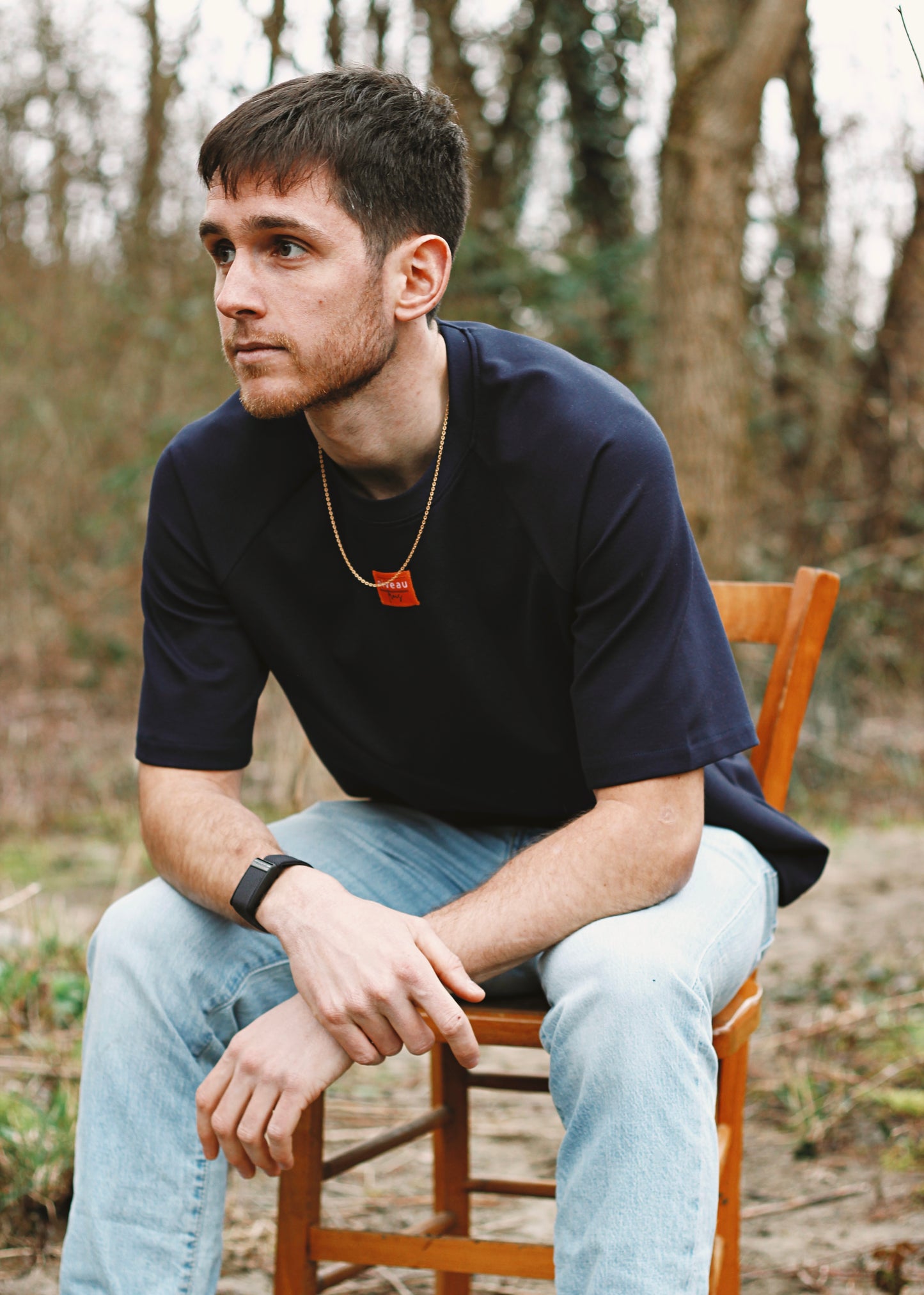 Homme assis sur une chaise, portant le tshirt Dama marine.