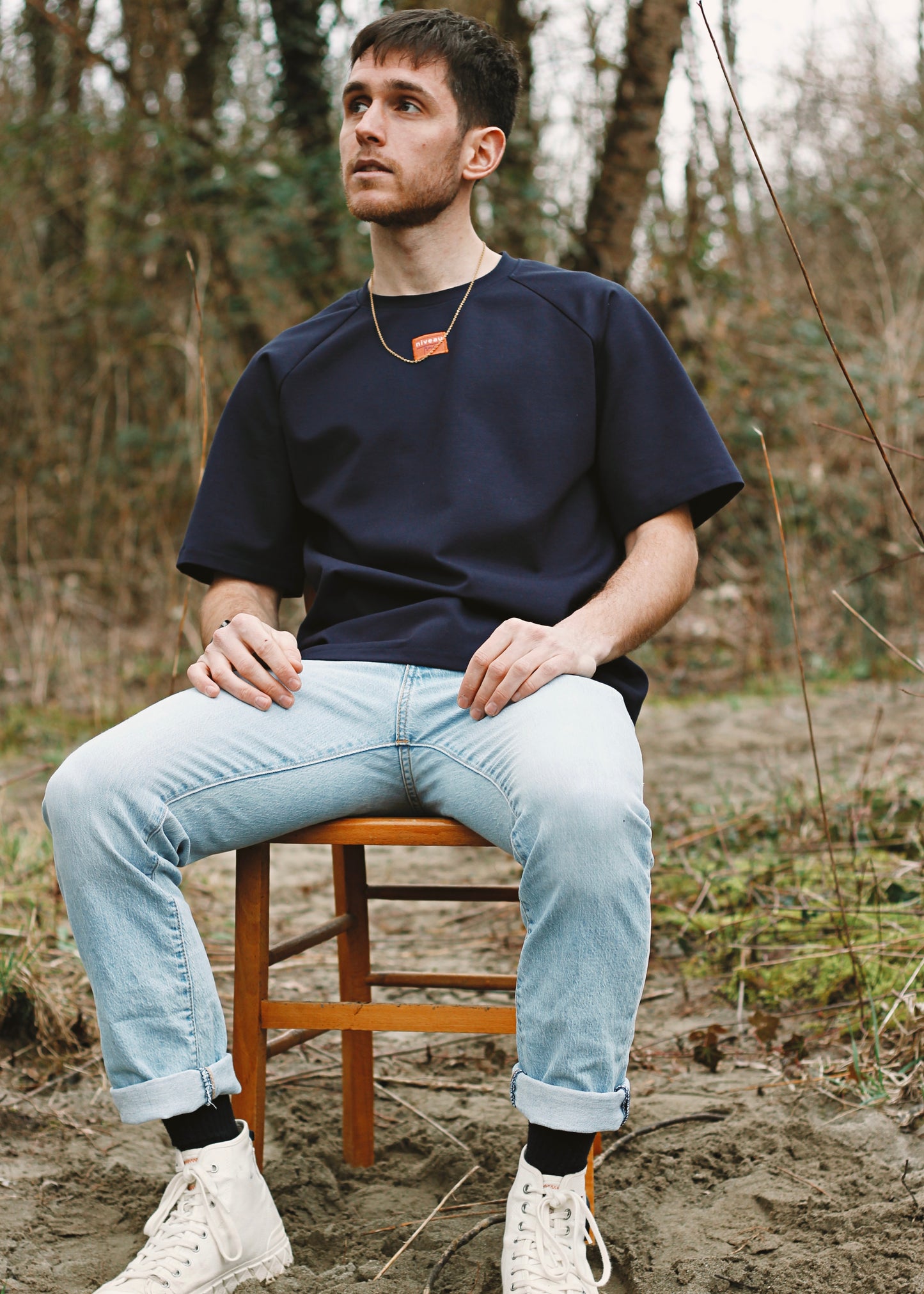 Homme assis sur une chaise, portant le tshirt Dama marine.