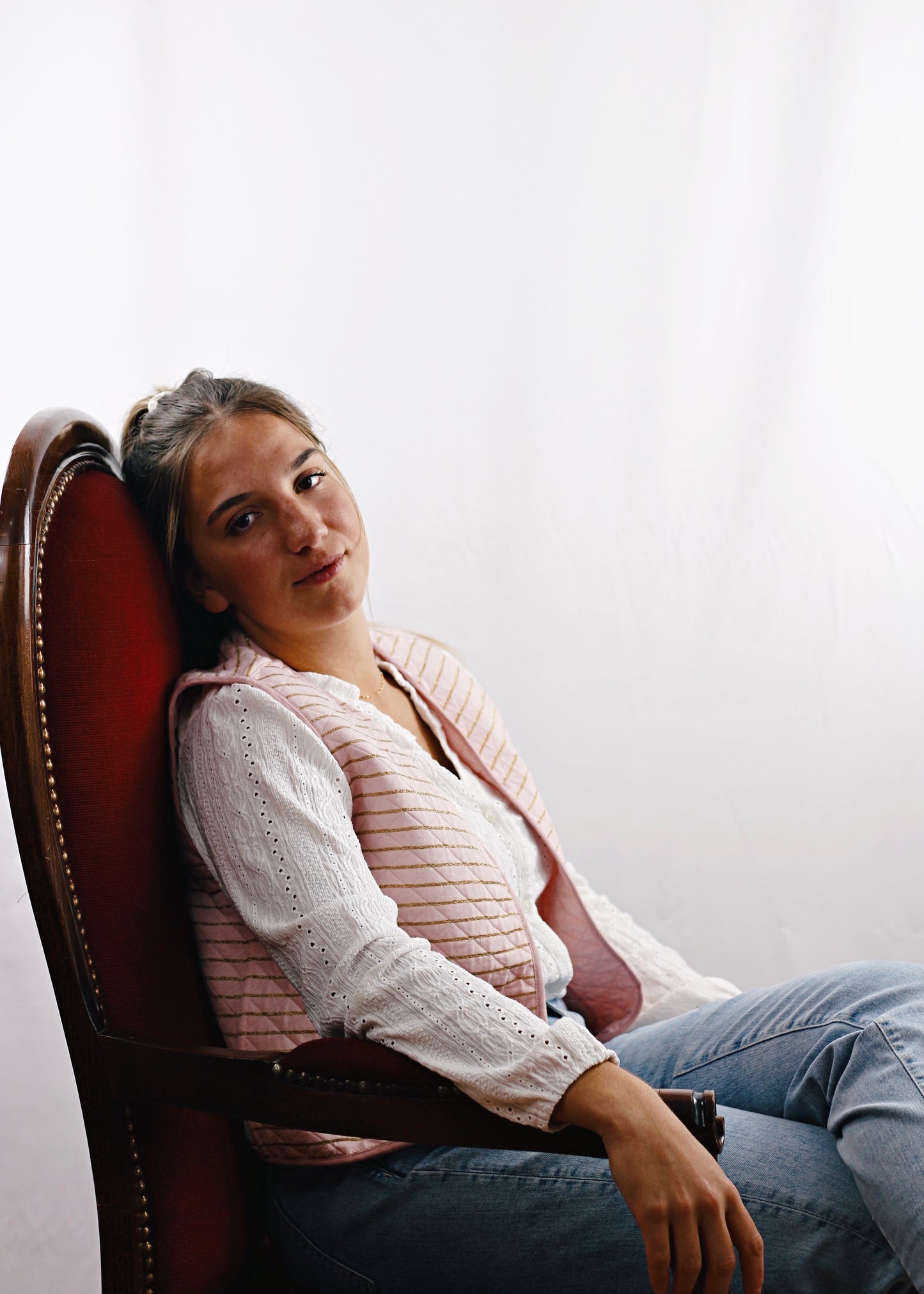 Gilet Alca en tissu molletonné rose réversible, jeune femme assise sur le fauteuil, rêveuse.