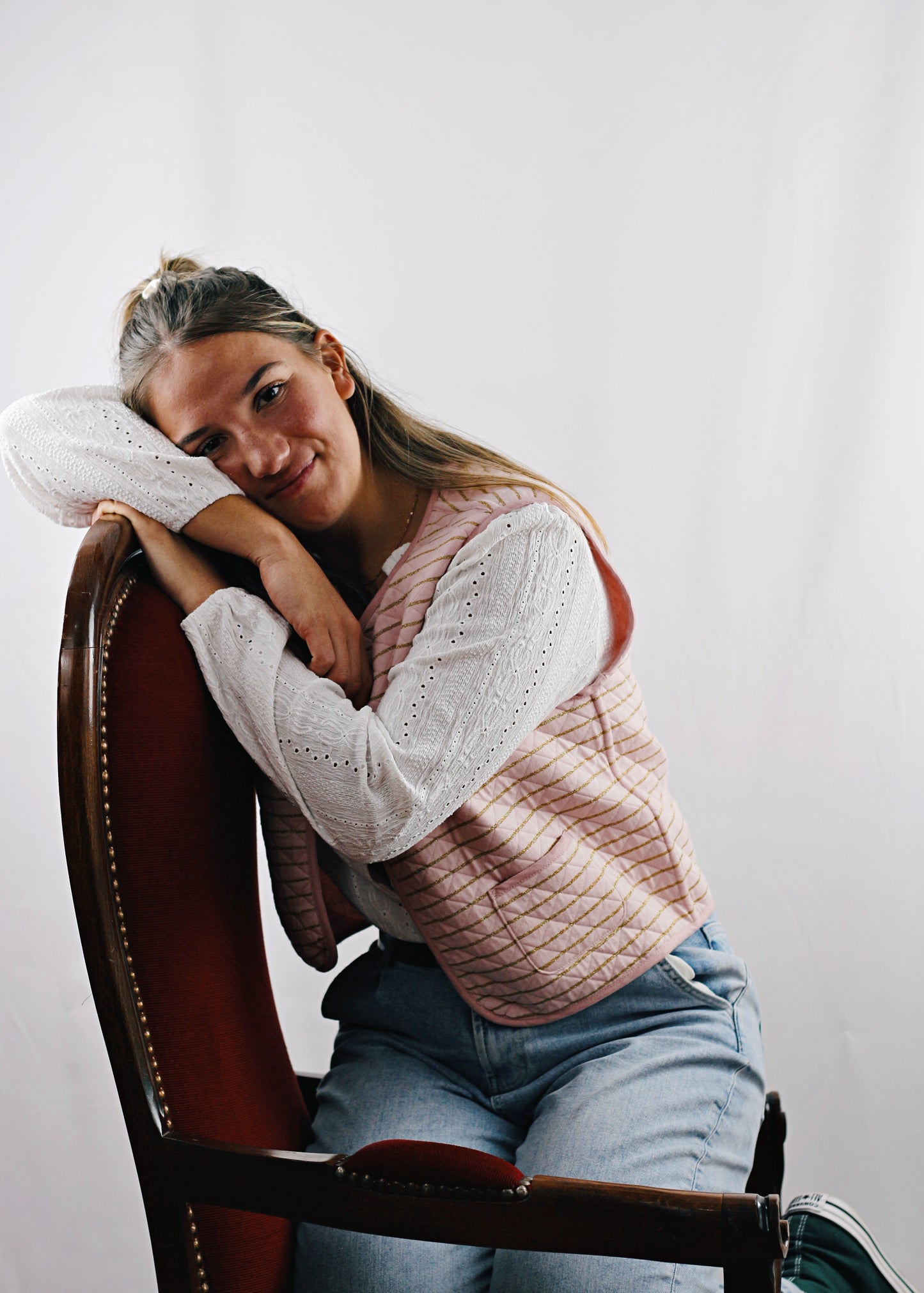 Gilet Alca en tissu molletonné rose réversible, jeune femme assise sur le fauteuil, la tête sur les coudes.