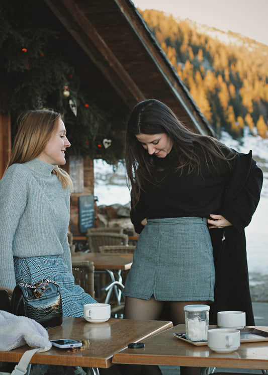 2 amis en jupe-short dans un café en montagne, ambiance hivernale au soleil couchant.