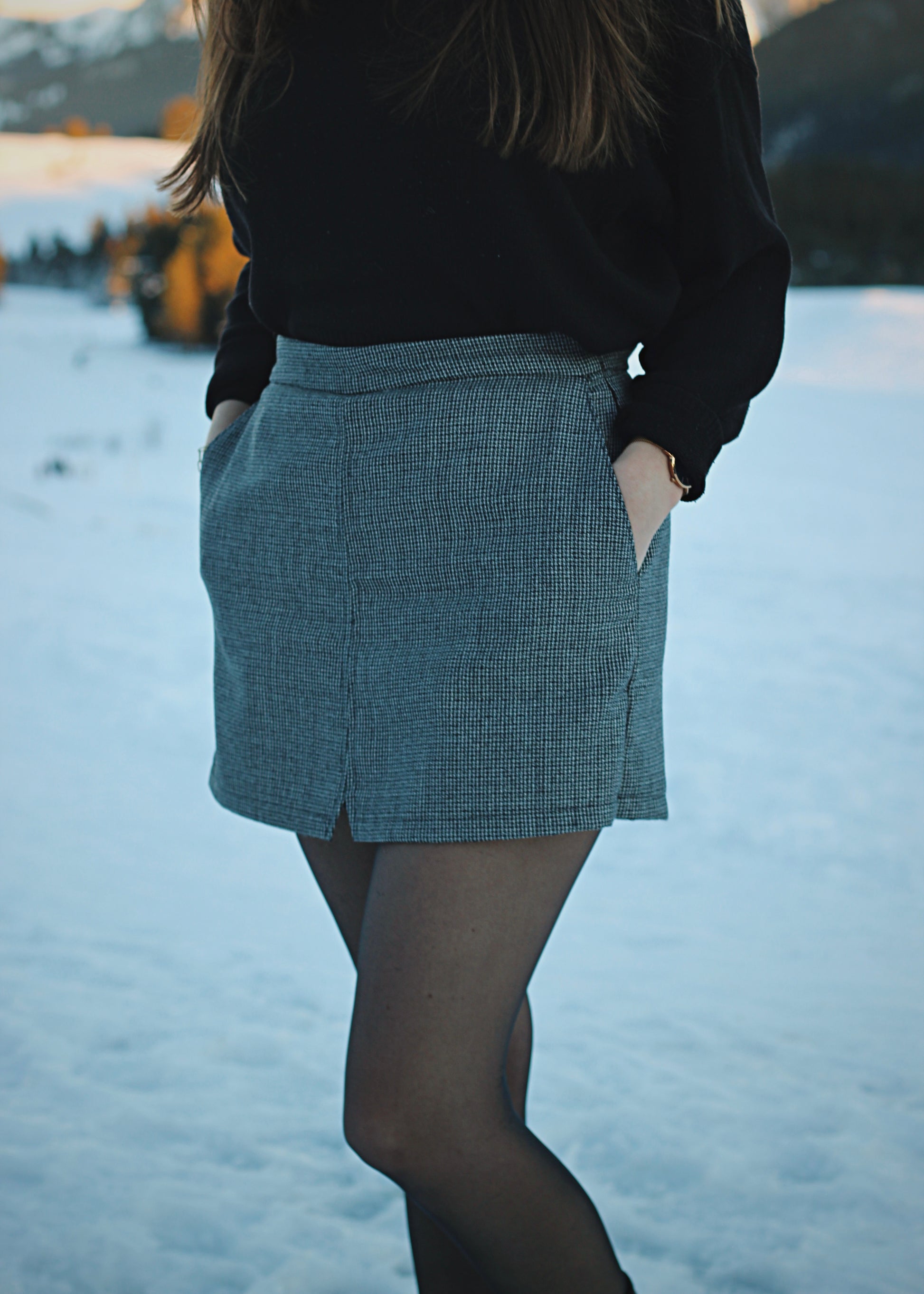 Jupe-short dans la neige, ambiance hivernale au soleil couchant, zoom sur la jupe de 3/4 devant.
