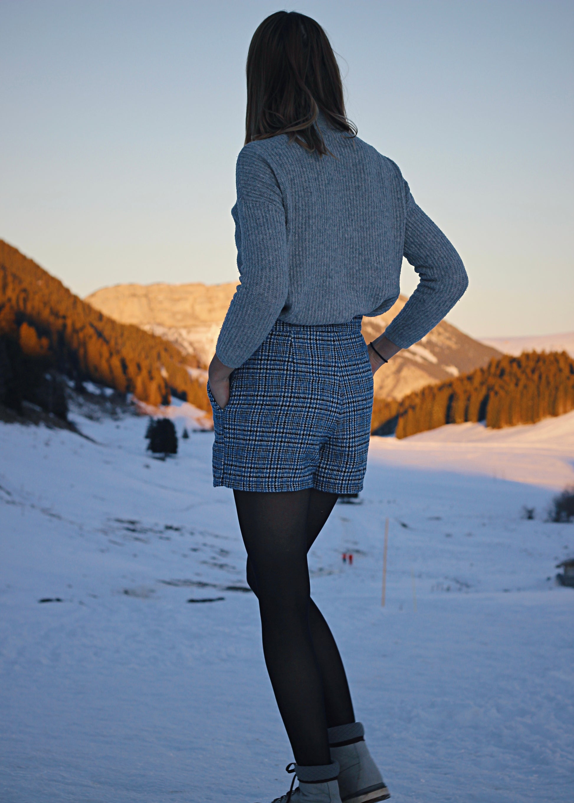 Jupe-short de dos, dans la neige, ambiance hivernale au soleil couchant.