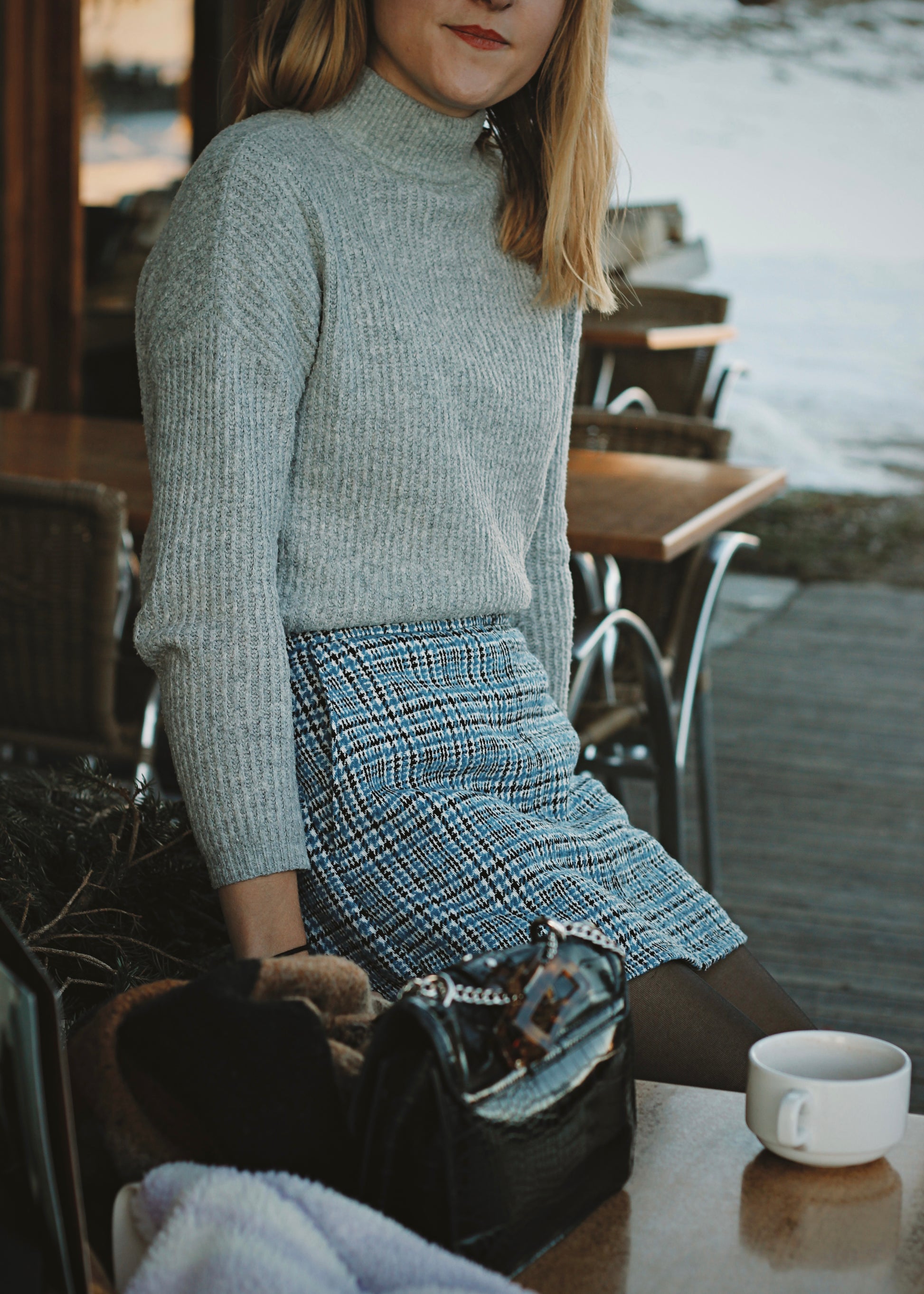 Femme en jupe-short dans un café en montagne, ambiance hivernale au soleil couchant.