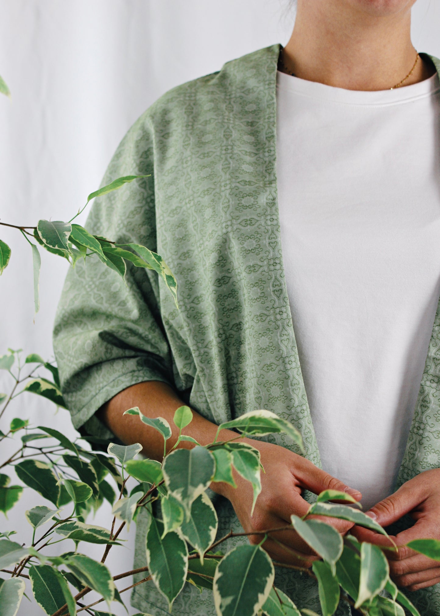 Kimono Sakura, zoom sur le tissu derrière les plantes, tissu vert à motifs.