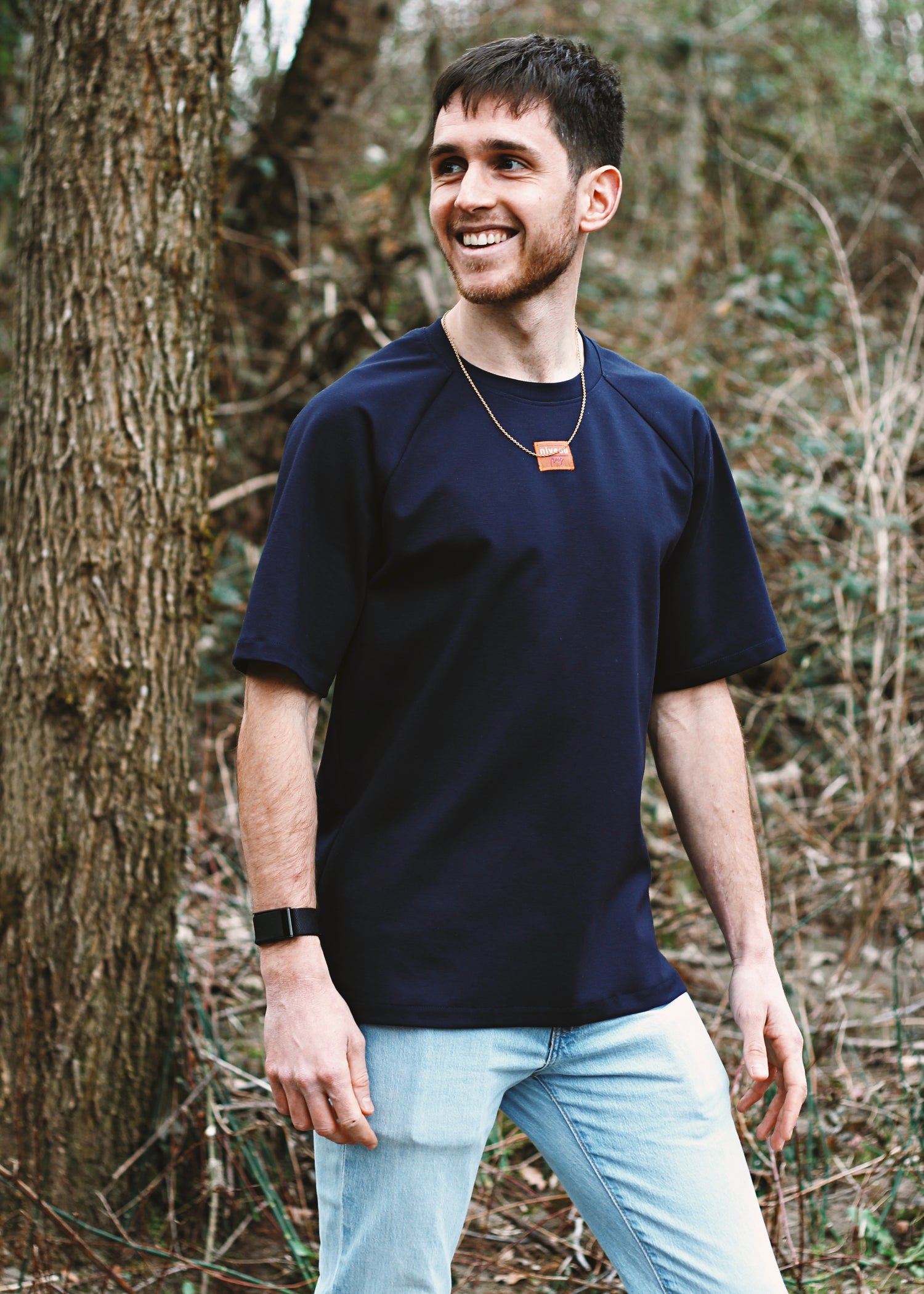 Homme souriant en forêt, portant le tshirt Dama marine.